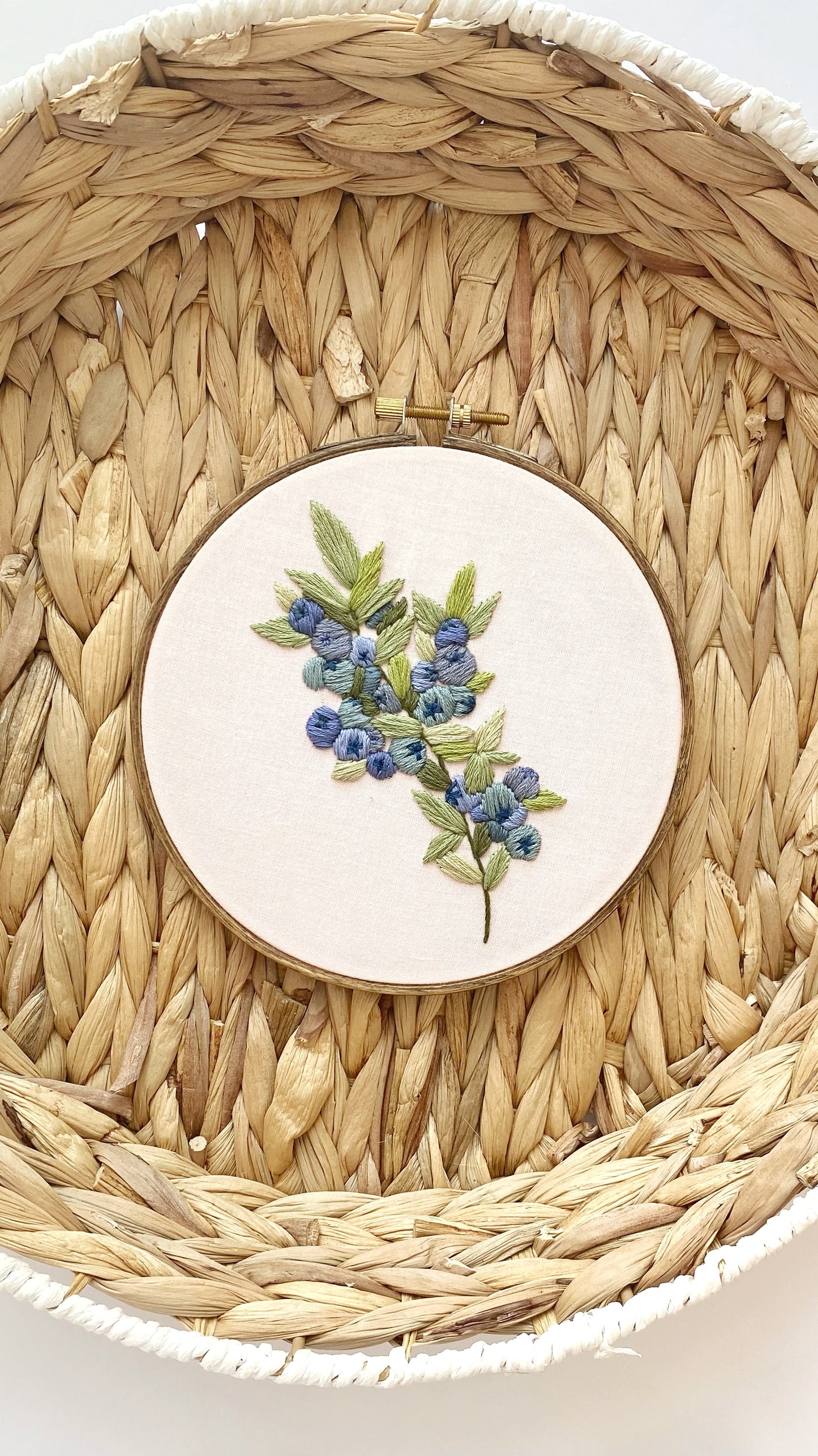 embroidery hoop featuring a blue berry design on a woven textured background for a beginner embroidery pattern.