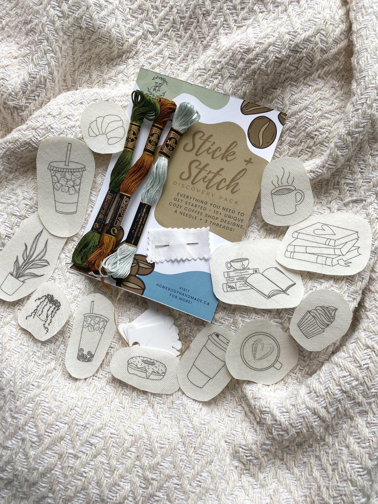 An overview of contents in a stick and stitch embroidery kit with pattern templates, DMC thread and a needle.