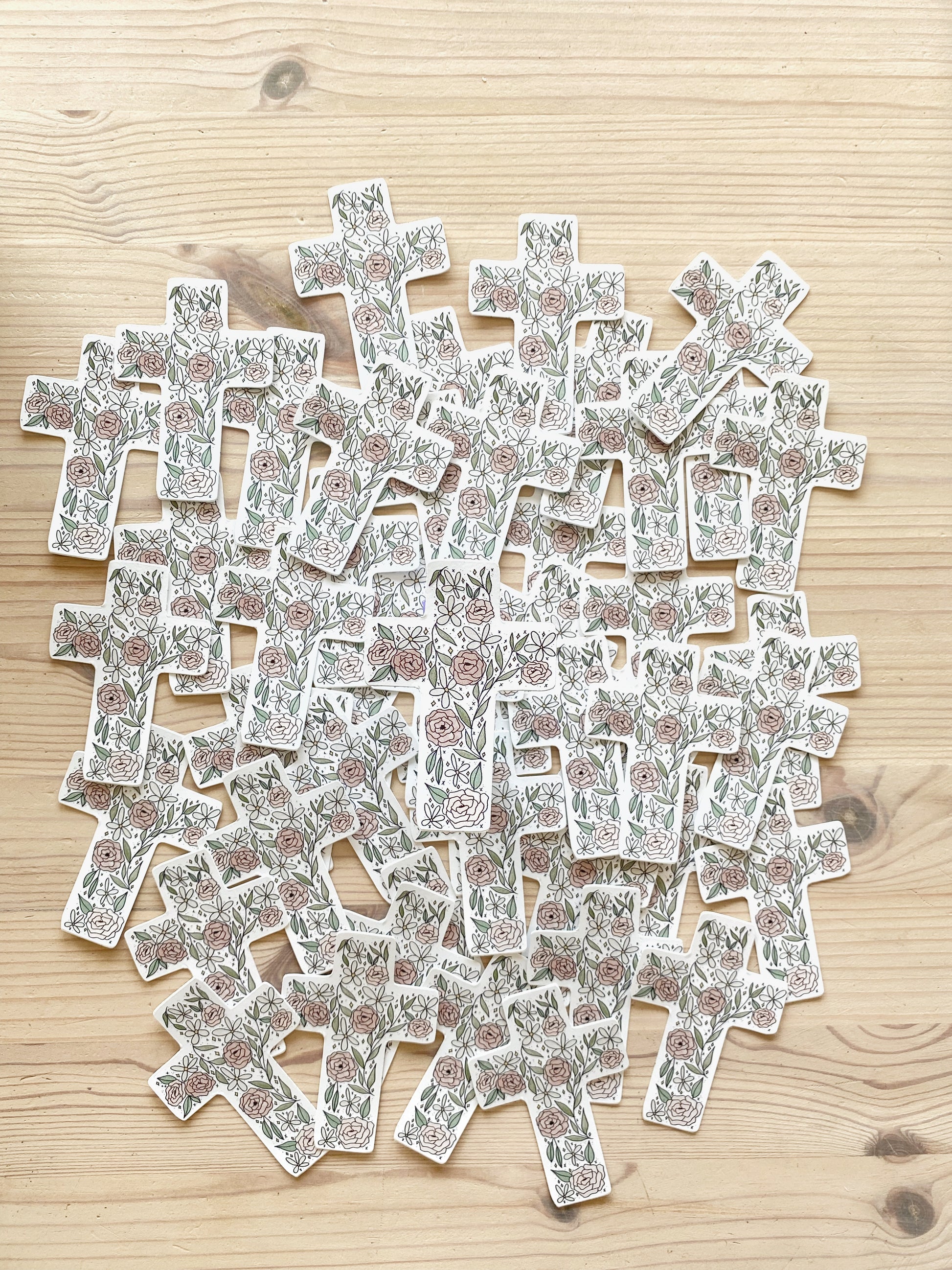 A floral cross sticker product photo featuring multiple matching stickers spread out in the background.