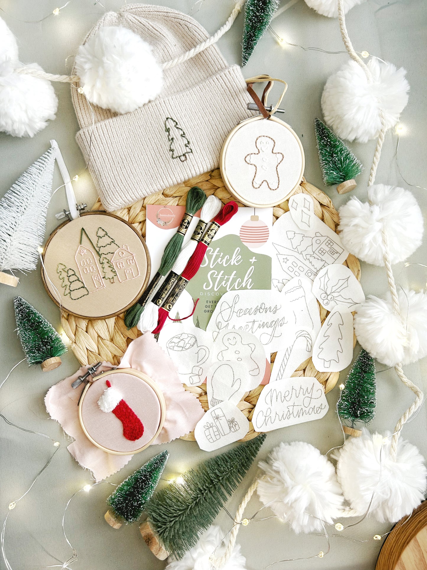 A collection of embroidery patterns and supplies for crafting, including a hoop, thread, and various embroidery designs with a Christmas theme.