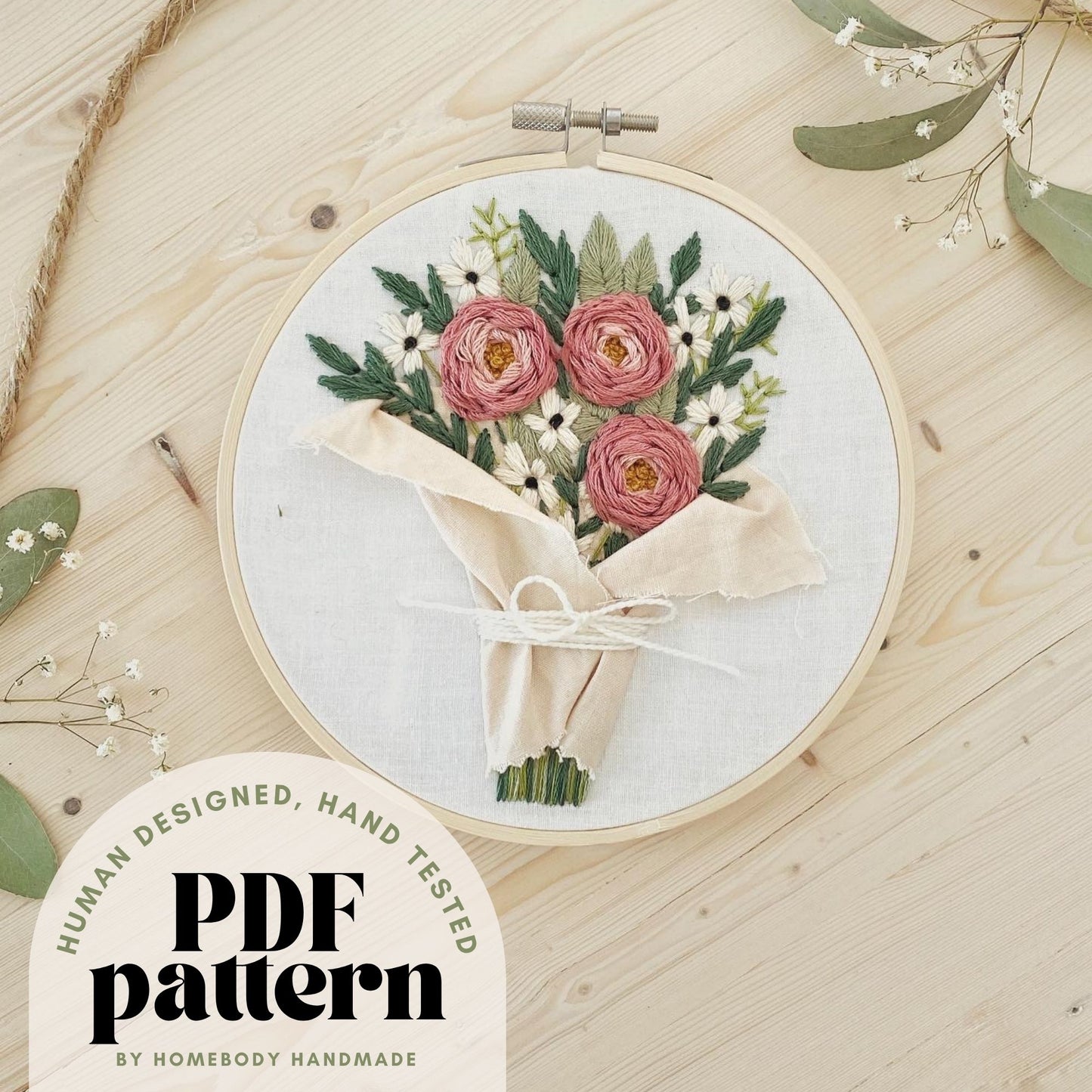 Embroidery hoop with floral design on a wooden surface, featuring 'PDF pattern' by Homebody Handmade.