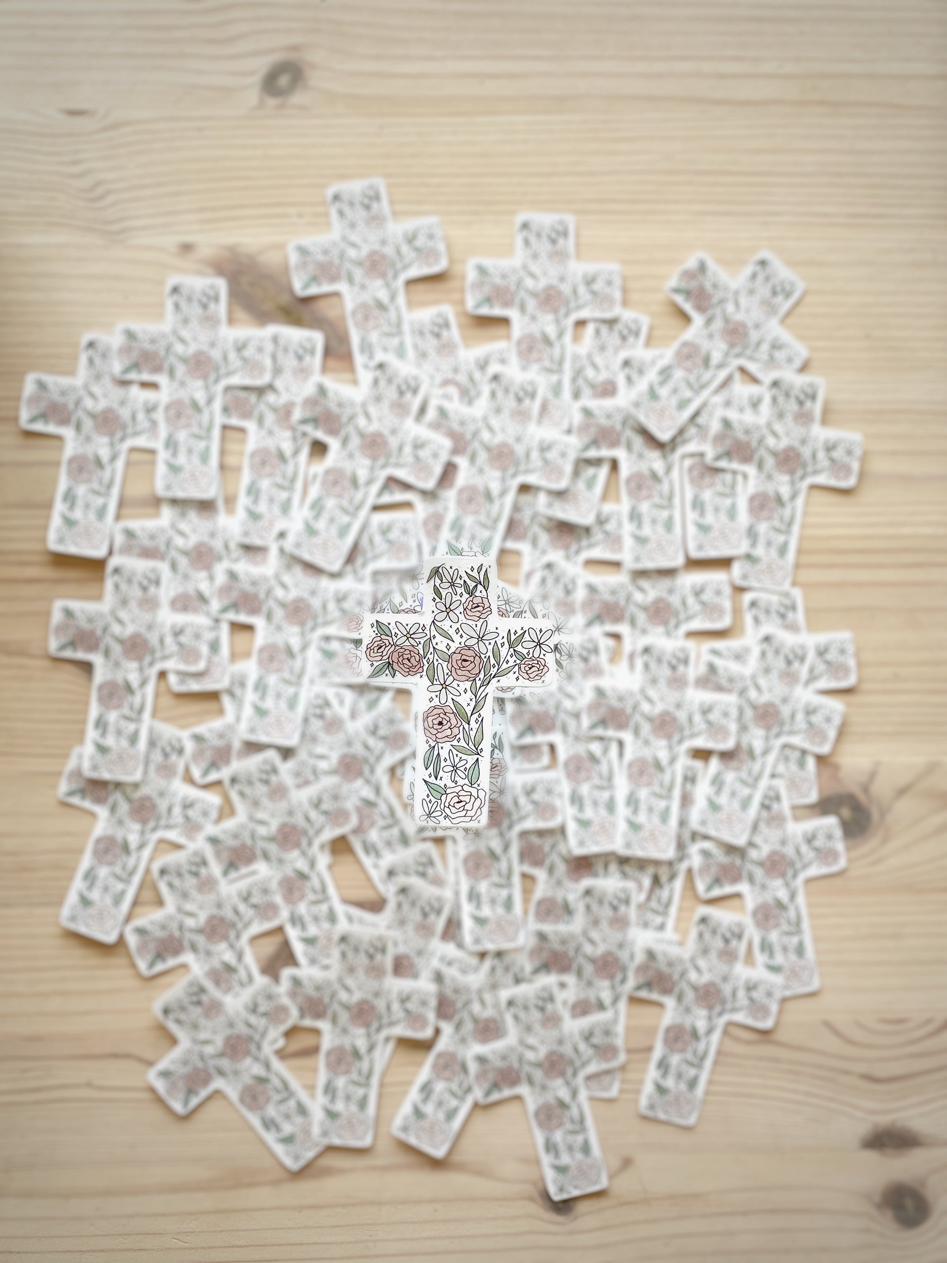 A floral cross sticker in focus with a blurred background of matching stickers.