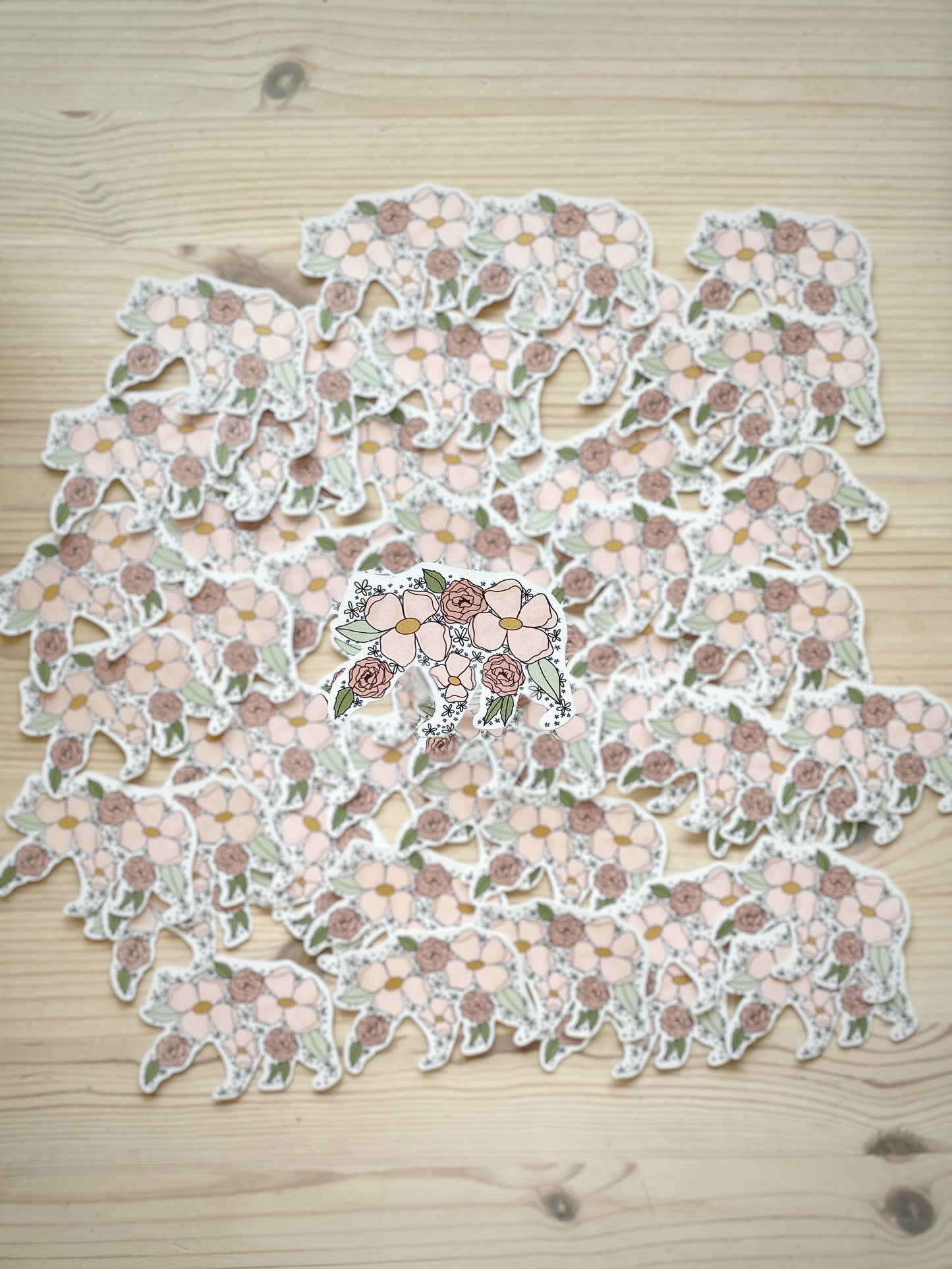 A floral mama bear silhouette sticker is featured with matching stickers spread out and blurred in the background.