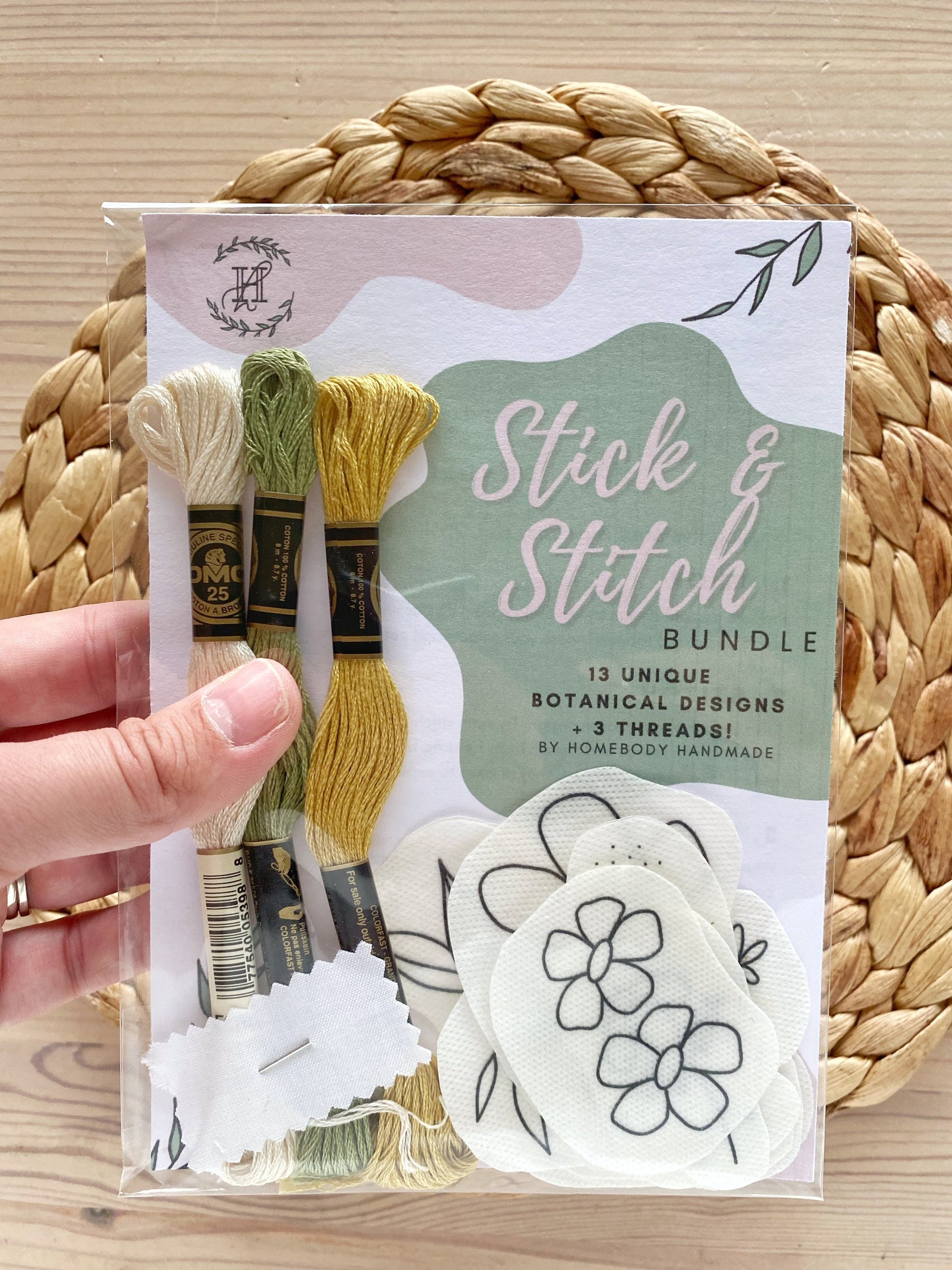 A hand is shown holding a floral stick and stitch embroidery pack for beginner embroidery.